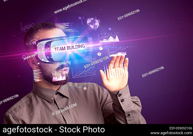 Businessman looking through Virtual Reality glasses with TEAM BUILDING inscription, new business concept
