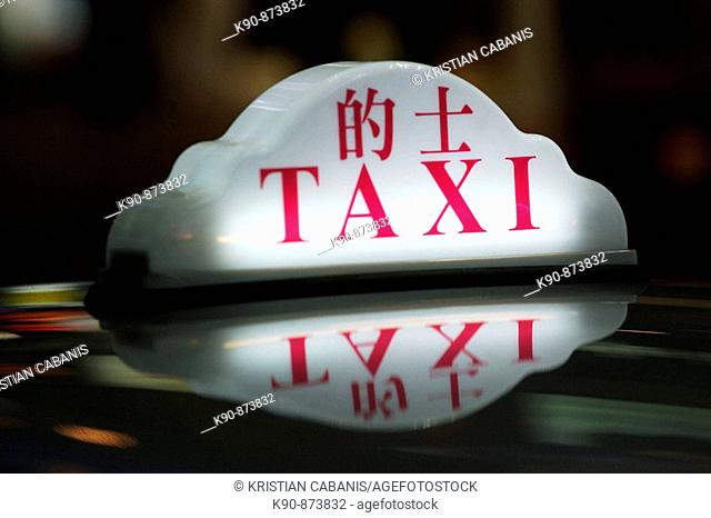 Close up of a taxi sign in chinese and latin letters on the roof of taxis, standing in a row in the amusement center of Wanchai, Hong Kong Island, Hong Kong