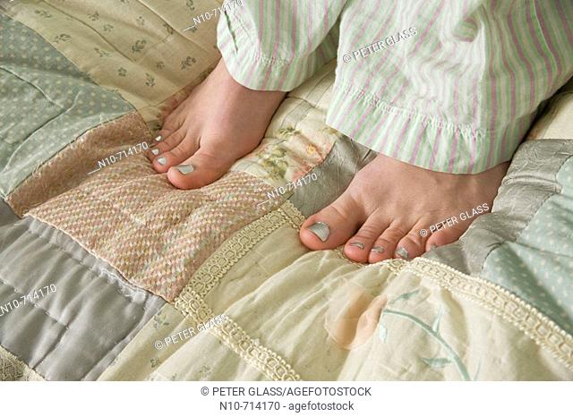 Close-up of a young woman's feet as she stands on her bed