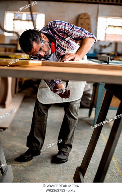 Carpenter working on wooden plank in workbench