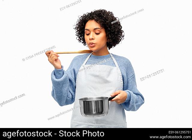 happy woman in apron cooking food in saucepan