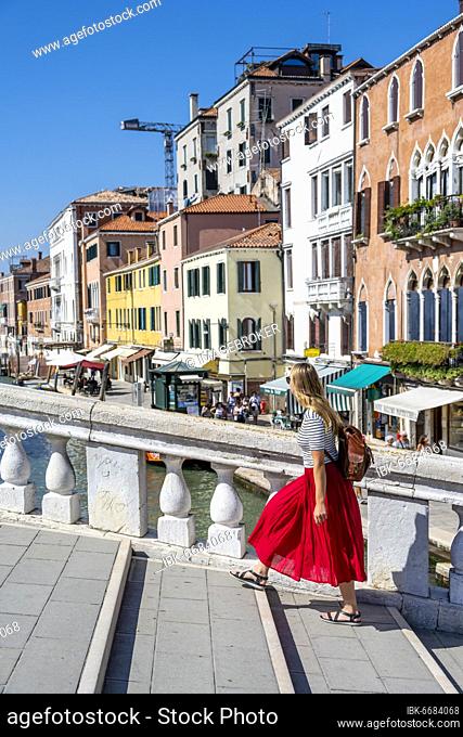 Young woman in red dress walking over Scalzi Bridge on the Grand Canal, Venice, Veneto, Italy, Europe