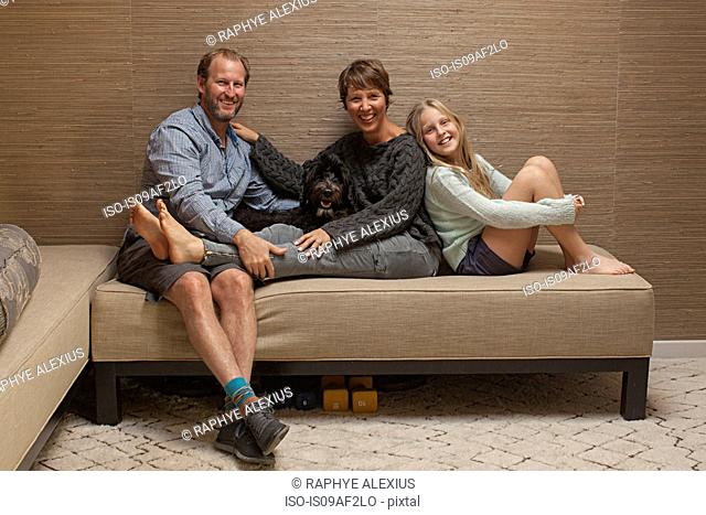 Portrait of parents and daughter on sofa