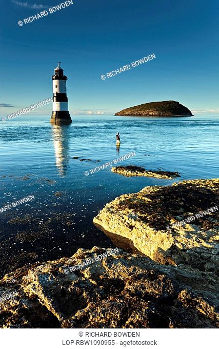 Wales, Anglesey, Penmon, A man fishing in front of Penmon lighthouse and Puffin Island at Penmon Point on the Isle of Anglesey