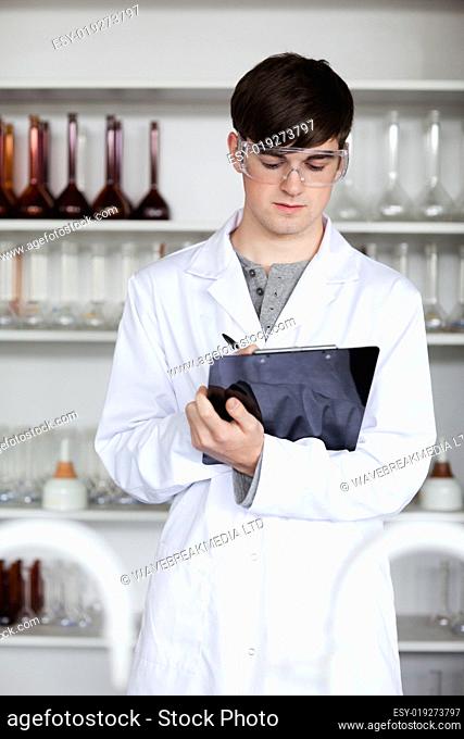 Portrait of a male scientist writing on a clipboard