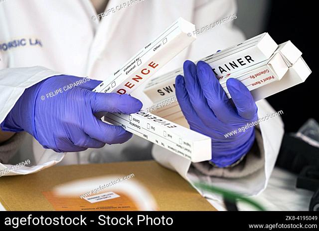 Police scientist holding boxes of DNA isotopes in his hands in a crime lab, conceptual image