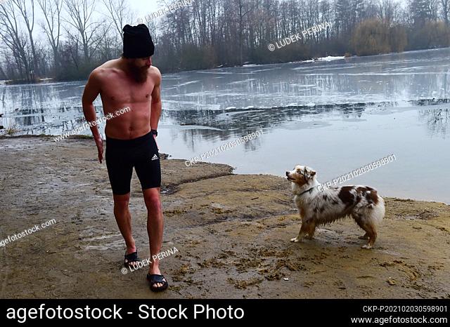 A young man bathed accompanied by his dog in ice water in the natural swimming pool Podebrady near Olomouc, Czech Republic, on February 3, 2021