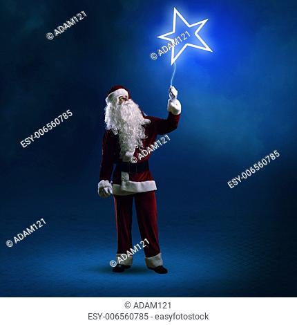 Santa Claus is holding a shining star sign on a string