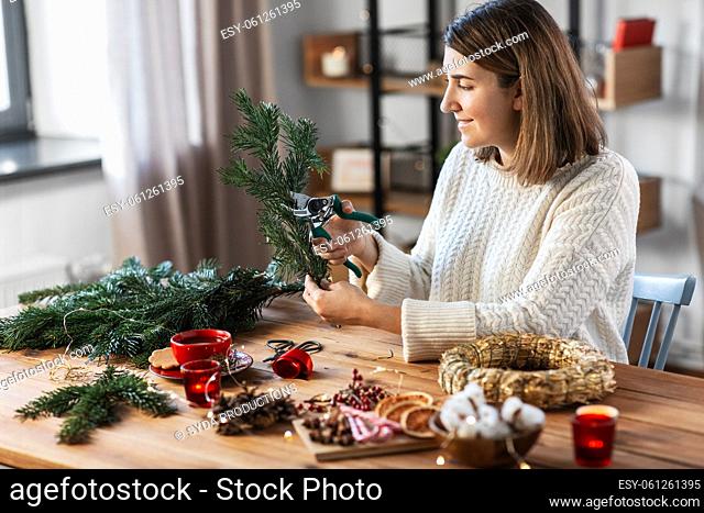 happy woman making fir christmas wreath at home