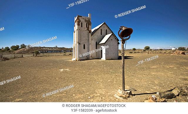 An old church with it's steeple missing, stands forlornly deserted in the hot sem-desert sunshine