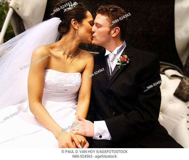 Bride and groom kissing in carriage