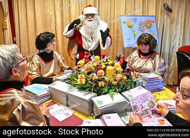 14 November 2023, Brandenburg, Himmelpfort: After arriving at the Christmas post office, Santa Claus stands with the angels who open and pre-sort his wish list...