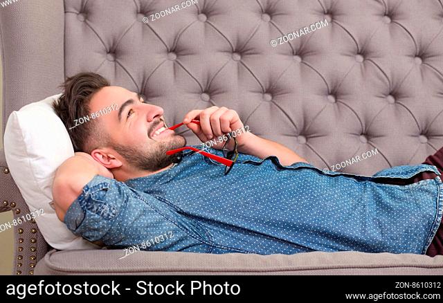 Male patient on a couch looking upward and talking with professional psychiatrist. Man holding glasses