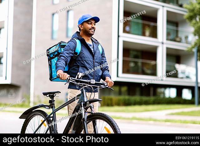 indian delivery man with bag and bicycle in city