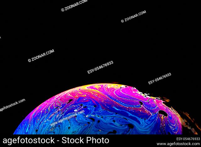 Rainbow soap bubble on a dark background. Close-up of colorful surface