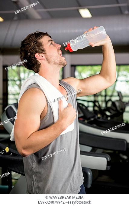 Man on treadmill drinking water at gym