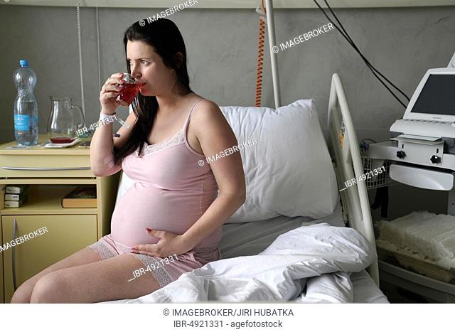 Pregnant woman sitting on sickbed in sickroom, high-risk pregnancy, Karlovy Vary, Czech Republic, Europe
