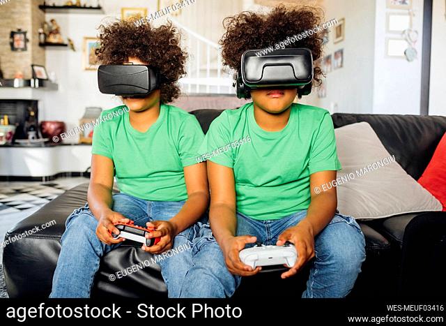 Twin brothers playing game wearing Virtual reality glasses at home