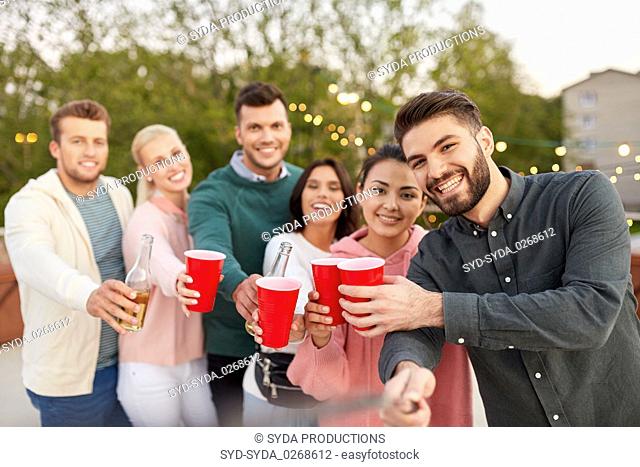 friends with drinks taking selfie at rooftop party