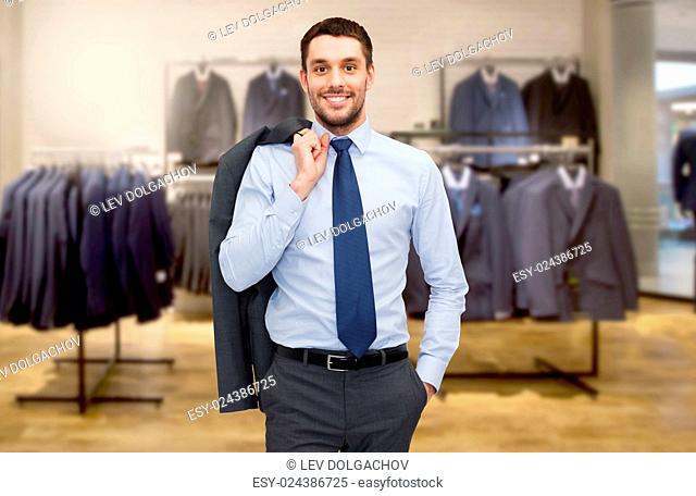 business, people, menswear, sale and clothes concept - happy young businessman over clothing store background