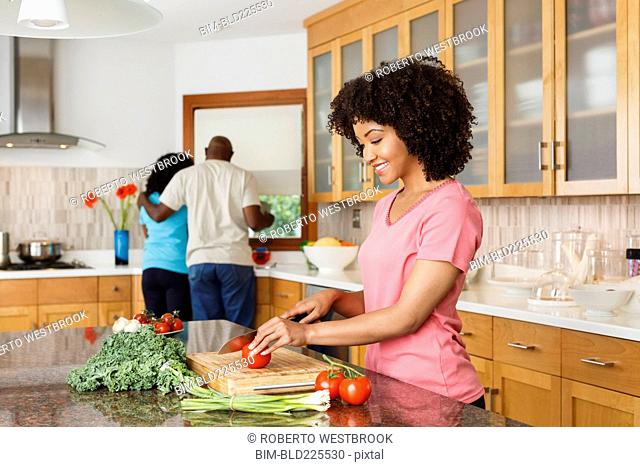 Black woman chopping tomato in kitchen