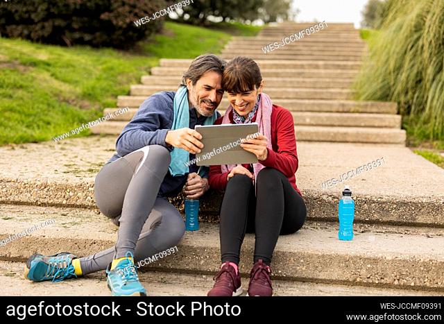 Happy mature couple using tablet PC on steps