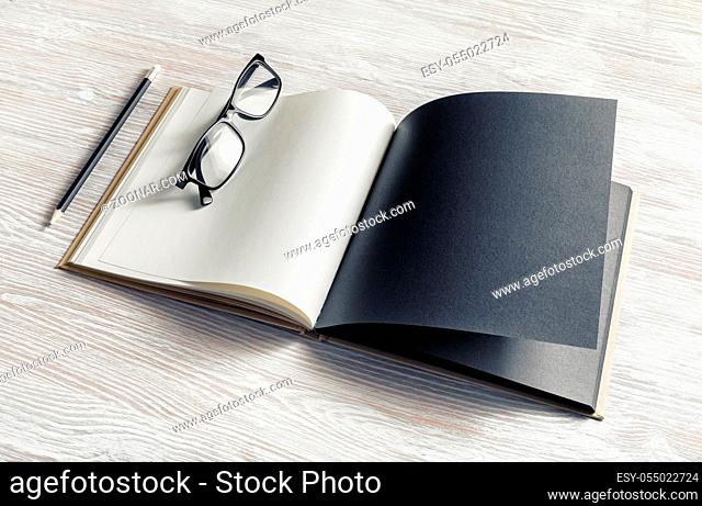 Mockup of opened blank booklet, pencil and glasses on light wooden background