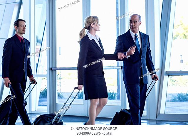 Businesspeople walking through airport with suitcases
