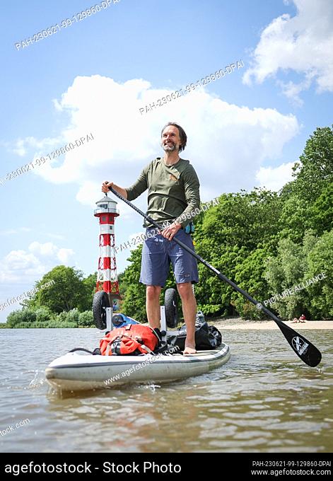 PRODUCTION - 14 June 2023, Hamburg: Christo Foerster, author, filmmaker and micro-adventurer, stands on his SUP on the Elbe River at Wittenbergen beach during a...