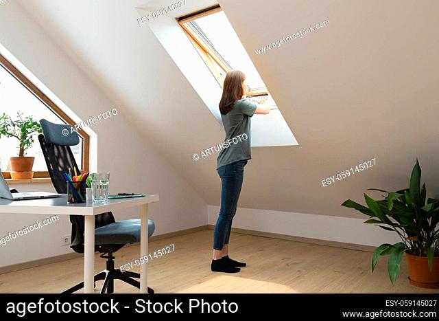 Women opening a window at home office and letting fresh air in. Healthy working environment in new normal business hours