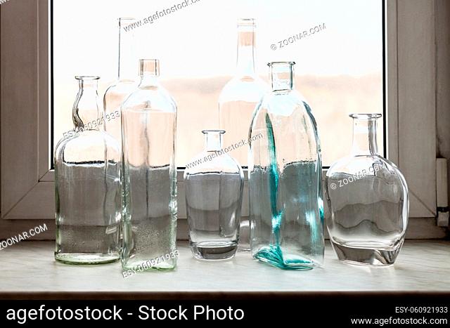 many empty drunk bottles on windowsill of home window on sunny spring day