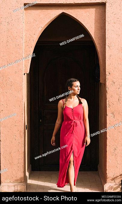 Portrait of young woman in front of entrance door, Merzouga, Morocco