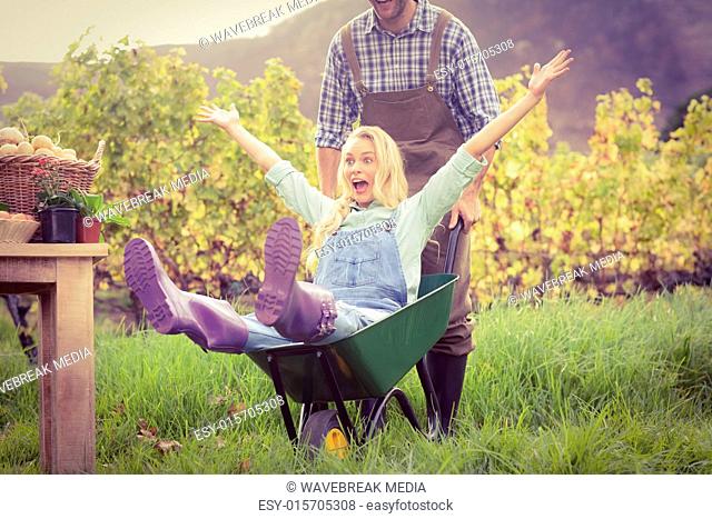 Happy couple in dungarees pushing a wheelbarrow