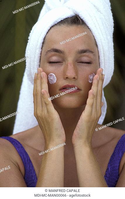Woman applying sun cream on her face