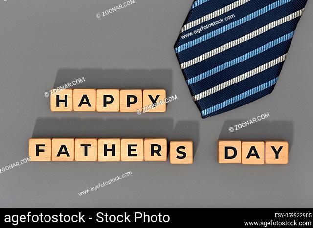 Happy Fathers Day blocks with tie on gray background. Celebration event background. Copy space