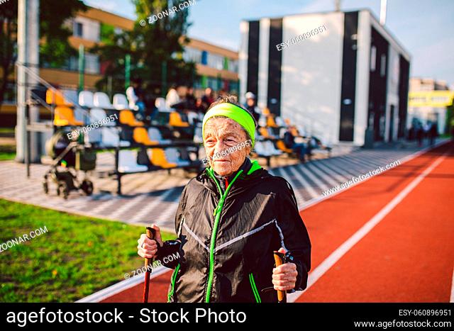 Active rest of the elderly theme. Sports and health in retirement. Caucasian very old woman with deep wrinkles doing Nordic walking exercises with sticks...