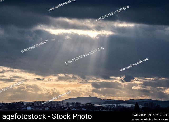 13 January 2021, Hessen, Groß-Umstadt: The clouds above the first hills of the northern Odenwald let rays of sunshine through onto the landscape