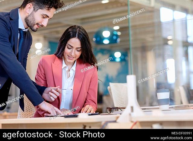 Male entrepreneur offering pen to female professional during agreement in office