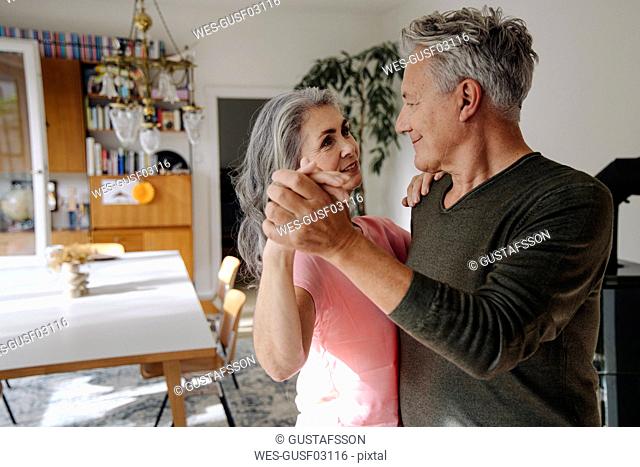 Senior couple dancing in living room at home