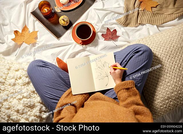woman drawing autumn leaf in sketchbook at home