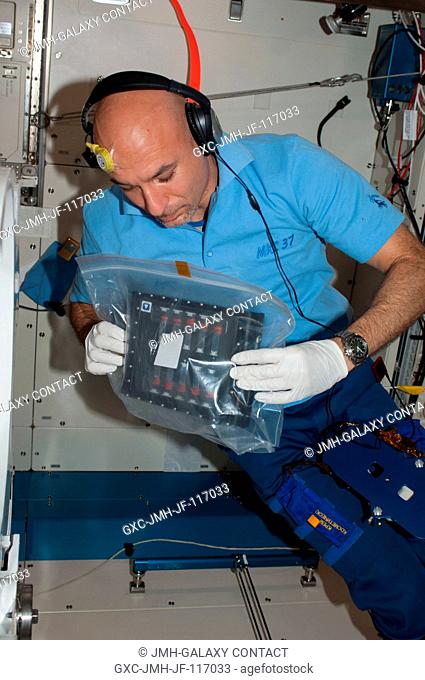 European Space Agency astronaut Luca Parmitano, Expedition 36 flight engineer, holds a bag while performing evening prep work in the Kibo laboratory of the...