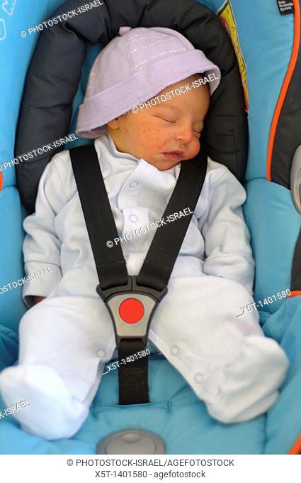 Baby boy sleeping strapped into a car seat