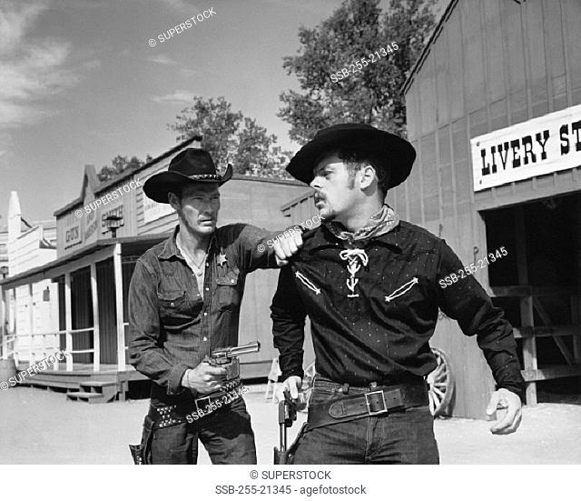 Sheriff pointing a pistol at a cowboy