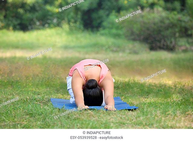 Woman practicing yoga in lawn