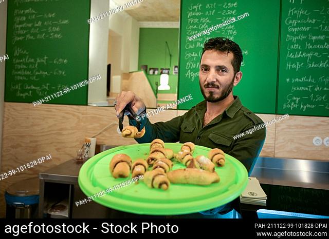22 November 2021, Saxony-Anhalt, Halle (Saale): Ismet Tekin shows Turkish delicacies that he offers in his café . The former KiezDöner Halle now opened as a...