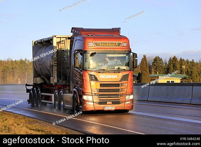 Bronze Next Generation Scania R580 truck of AH Trans Oy hauls chemical liquid container along highway in winter sunlight. Salo, Finland. Jan 24, 2020
