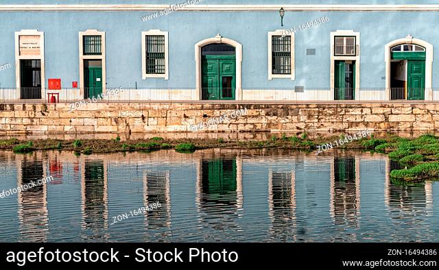 Lisbon, Portugal - 15 December 2020: building with blue and white walls and green doors reflected in a calm pond in the foreground