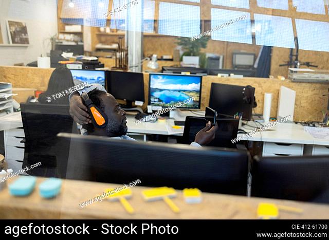 Businessman in headset using smart phone in open plan office