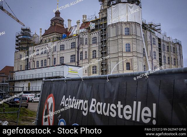PRODUCTION - 11 December 2023, Mecklenburg-Western Pomerania, Güstrow: A sign reading ""Attention construction site"" hangs in front of the castle