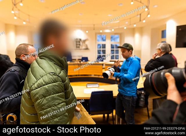 11 December 2023, Baden-Württemberg, Waldshut-Tiengen: A defendant is led into the courtroom of the Waldshut district court while Swiss media representatives...